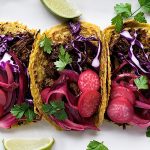 Closeup of barbacoa brisket tacos topped with pickled radishes, cabbage, and cilantro