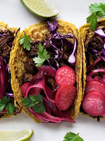 Closeup of barbacoa brisket tacos topped with pickled radishes, cabbage, and cilantro
