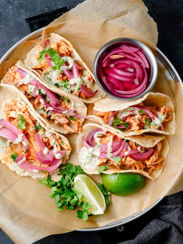 Tray filled with buffalo chicken tacos and pickled onions