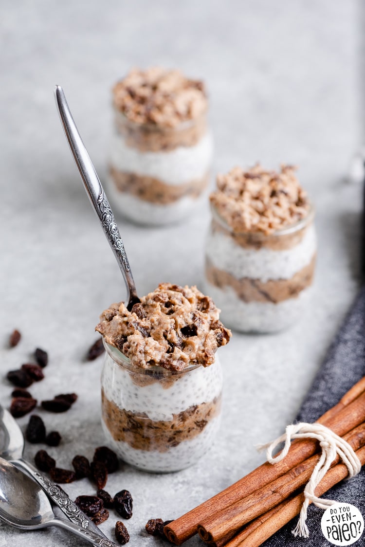 Jars of paleo chia pudding with spoons, raisins, and cinnamon sticks