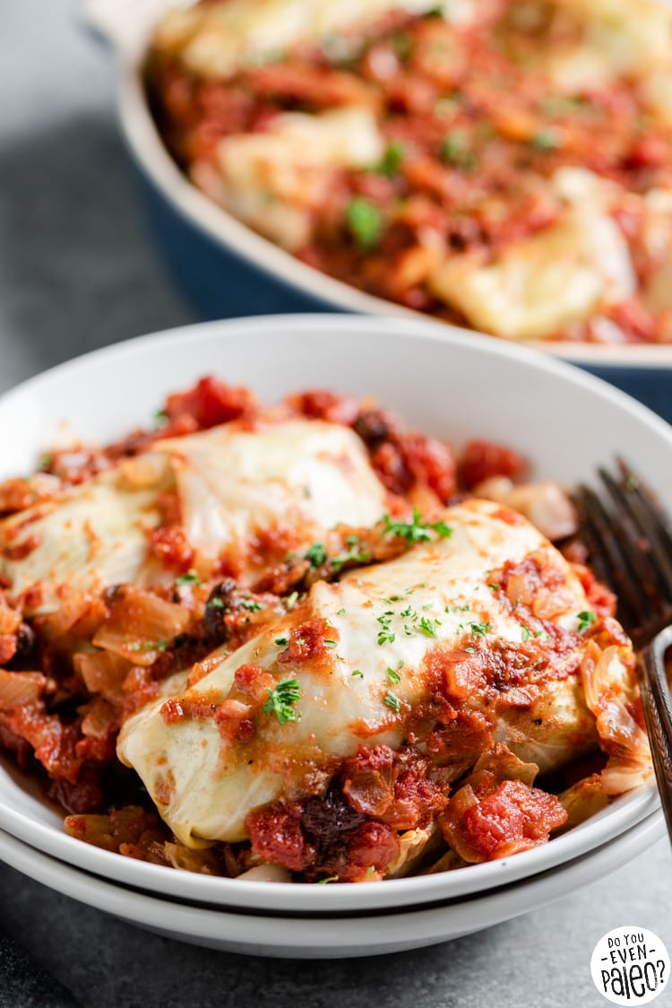 Cabbage rolls in a bowl, with the casserole dish in the background
