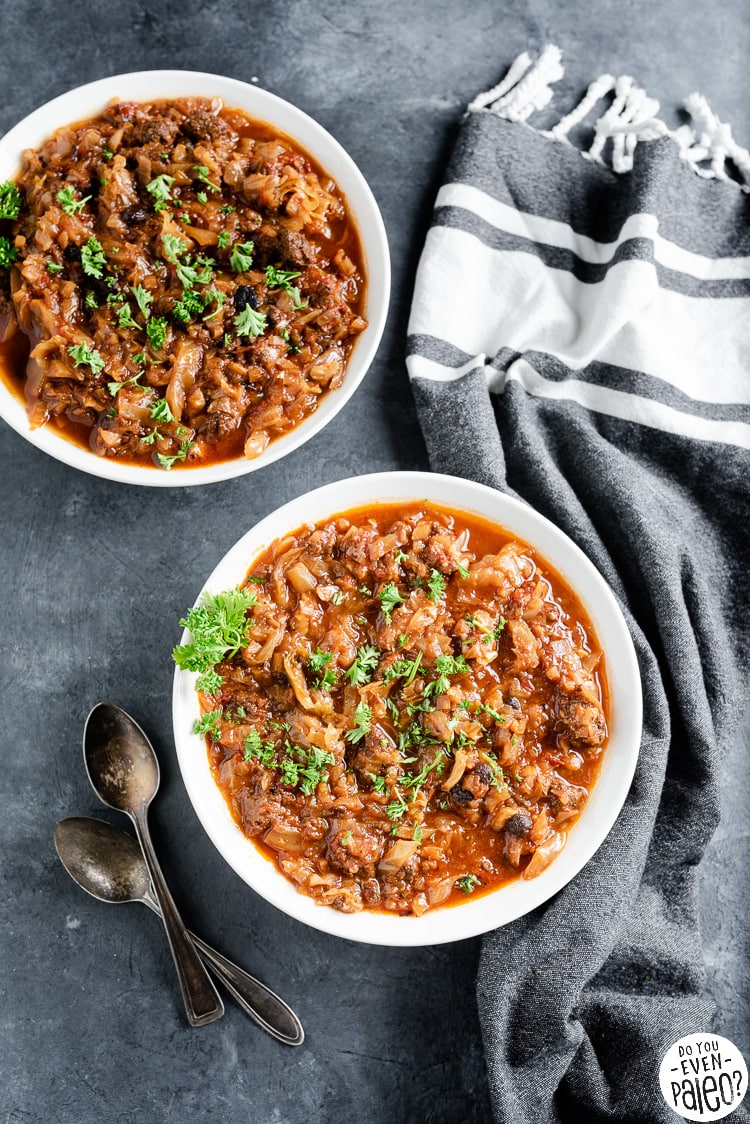 Two bowls of slow cooker cabbage roll soup with vintage spoons and a table linen