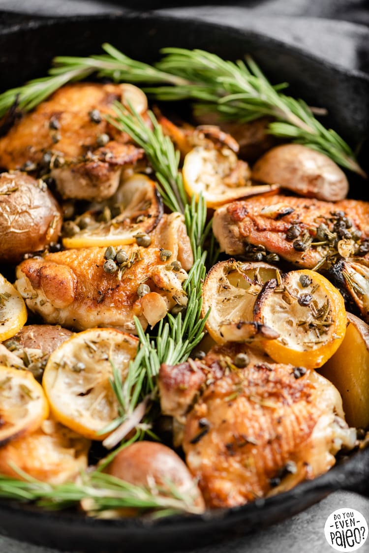 Closeup of lemon rosemary chicken thighs and potatoes in a cast iron skillet