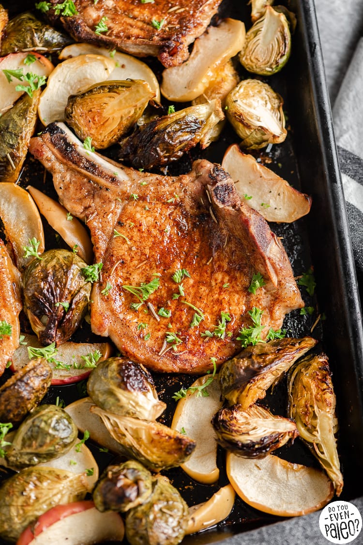 Closeup of pork chops and vegetables on a sheet pan