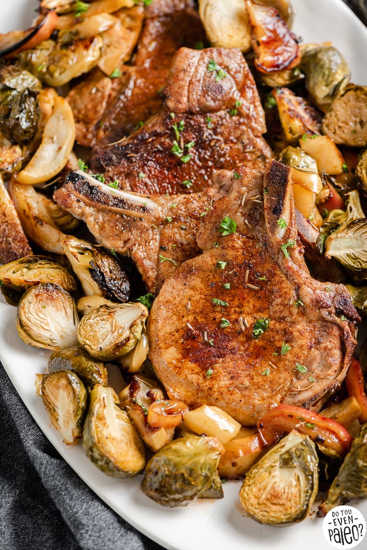 Closeup of cooked pork chops with brussels sprouts and apples