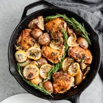 Overhead view of rosemary lemon chicken thighs with potatoes in a cast iron skillet