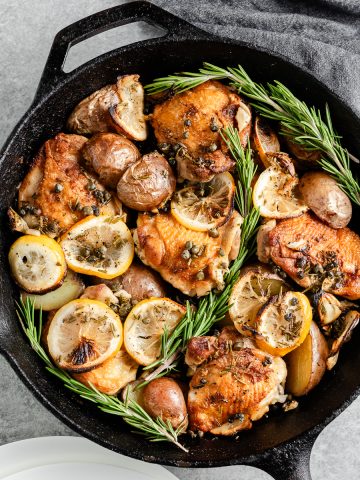 Overhead view of rosemary lemon chicken thighs with potatoes in a cast iron skillet
