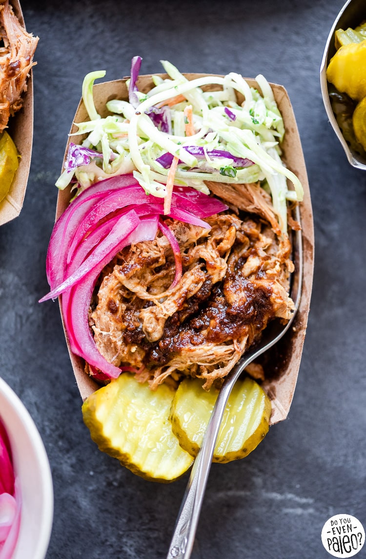 Serving of chipotle pulled pork with coleslaw, pickled onions, and pickles