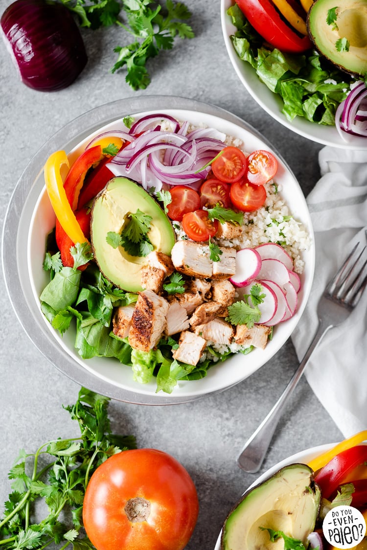 Low carb chipotle chicken burrito bowl surrounded by fresh produce