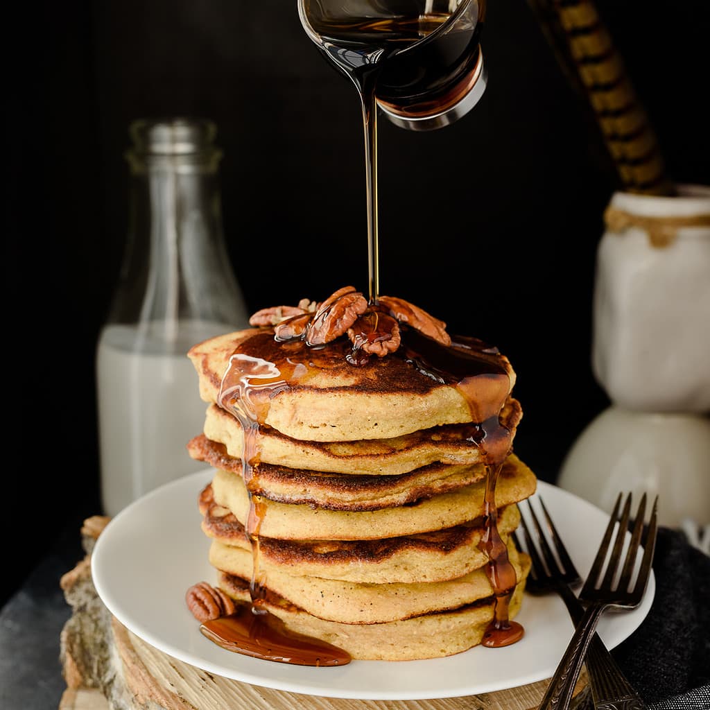 Stack of gluten free plantain pancakes with maple syrup being poured overtop.