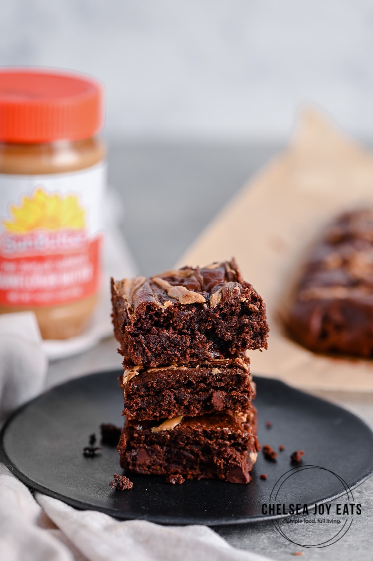 Stack of paleo brownies with a jar of SunButter in the background