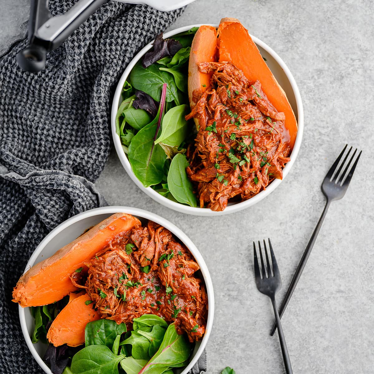 Bowls of greens and roast sweet potatoes topped with slow cooker BBQ shredded chicken