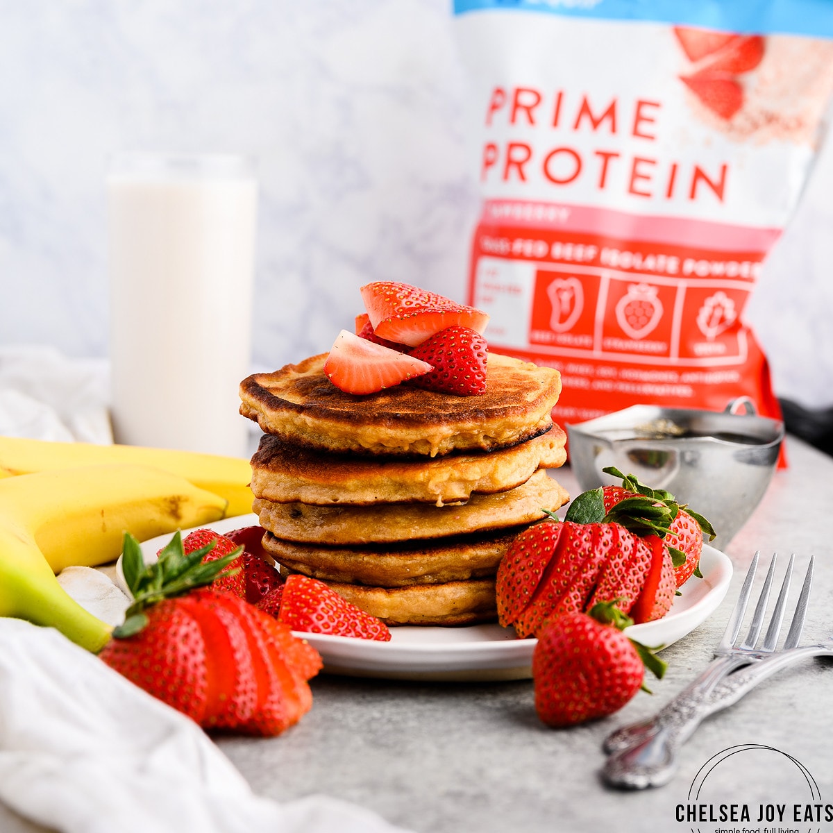 Protein powder pancakes stacked on a plate and garnished with fresh strawberries