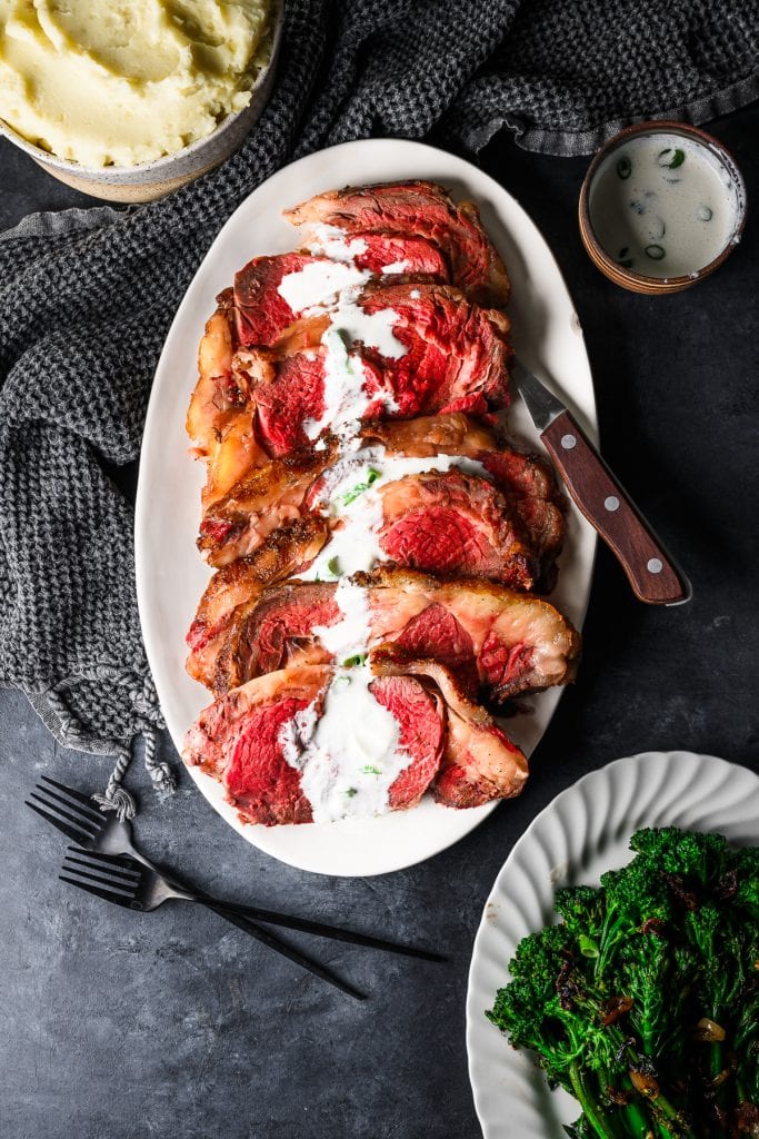 overhead view of sliced roasted prime rib with horseradish sauce