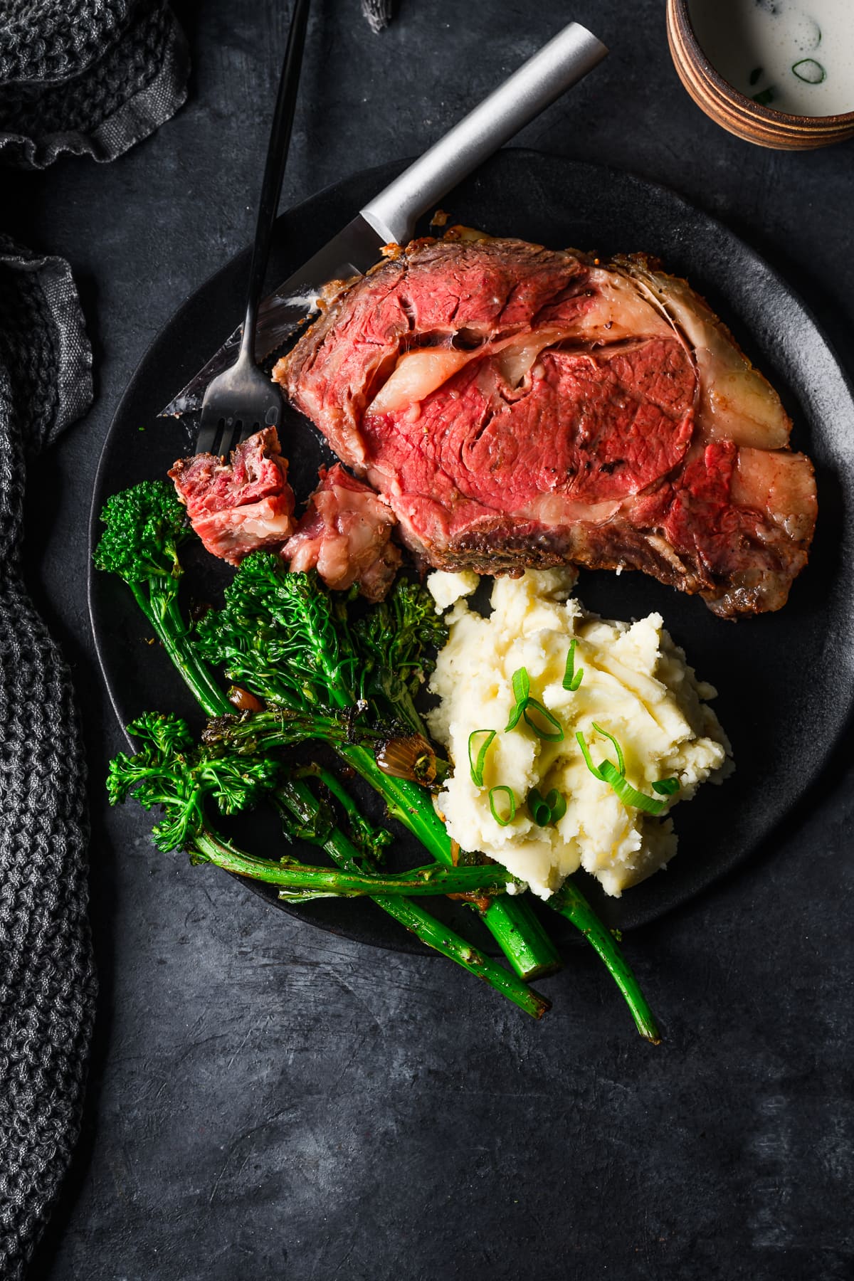 Moody place setting with broccolini, mashed potatoes, and prime rib