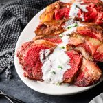 Closeup of reverse sear roasted prime rib sliced and smothered with horseradish sauce