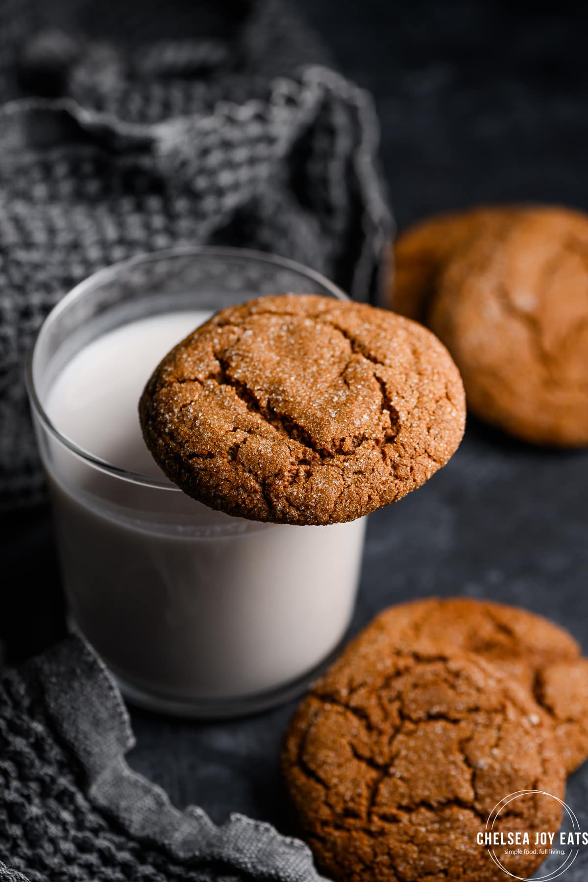 Gluten free molasses cookie balanced on the rim of a glass full of milk