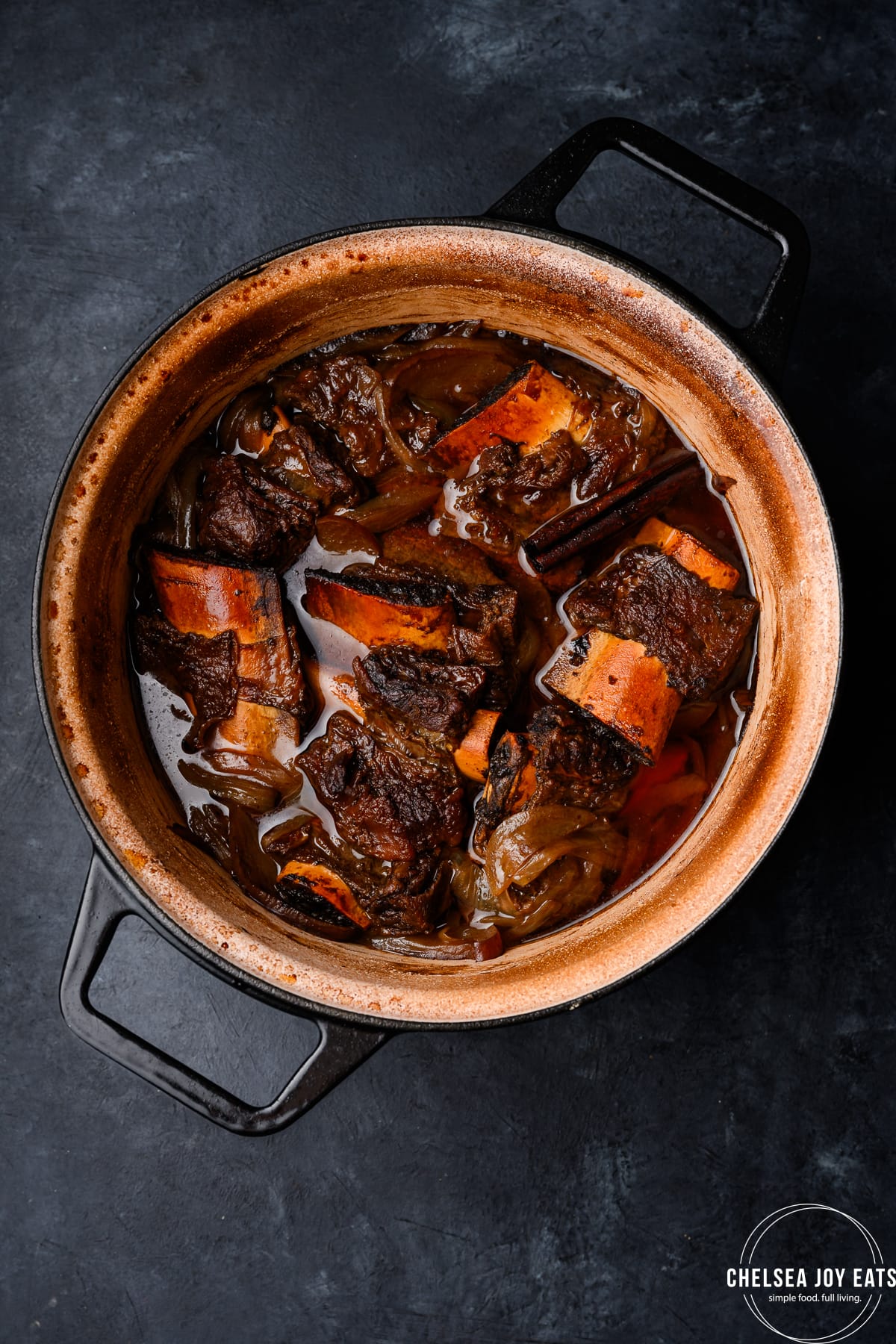 Braised short ribs in a Dutch oven on a dark background