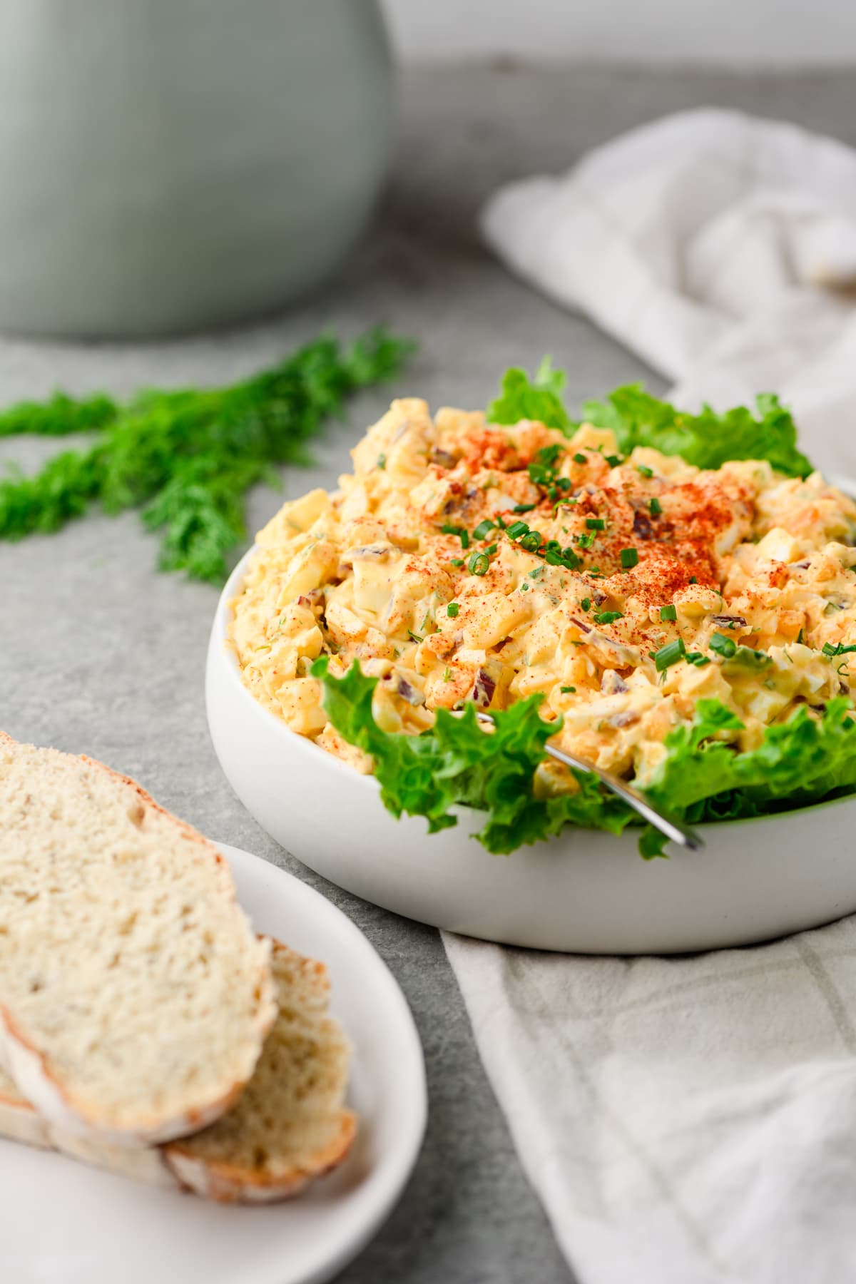 Egg salad made with cottage cheese served in a bowl over lettuce, with sourdough bread in the foreground