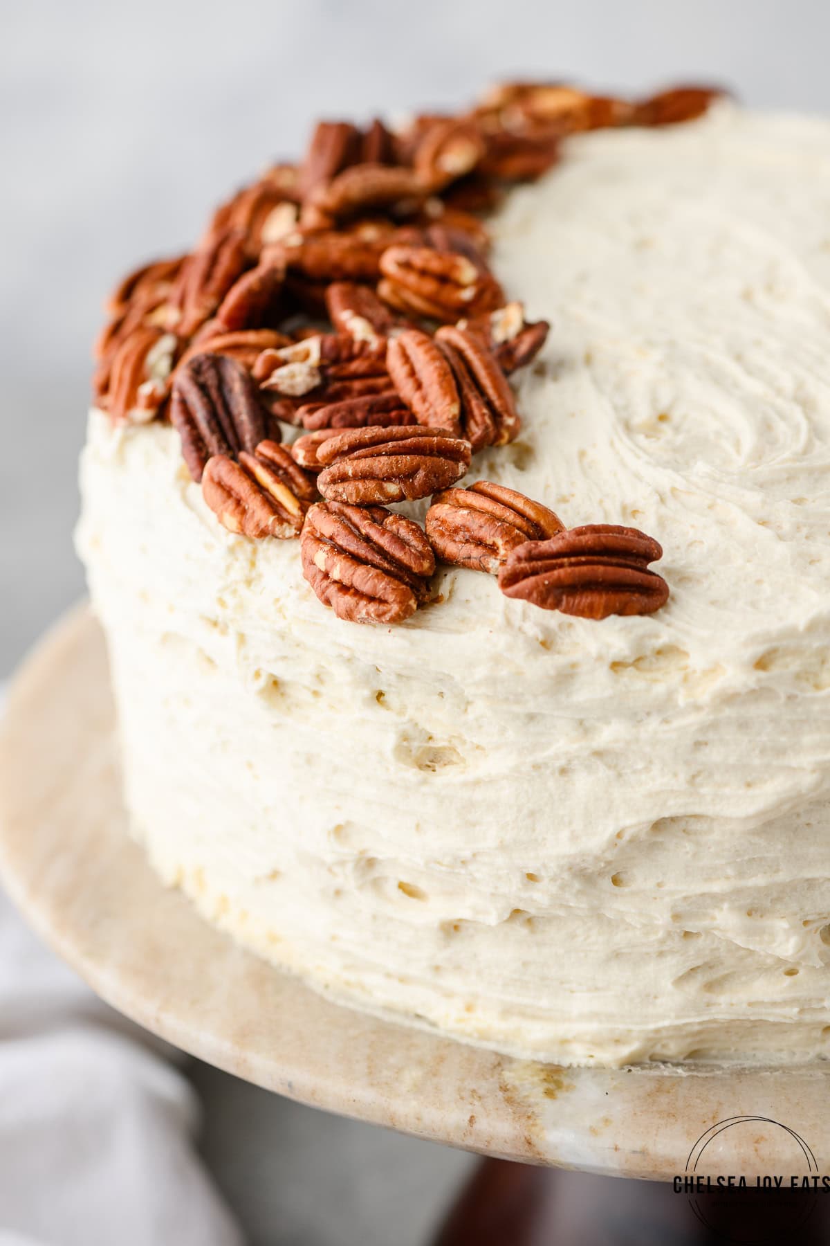 Closeup of frosted gluten free hummingbird cake with toasted pecans as garnish
