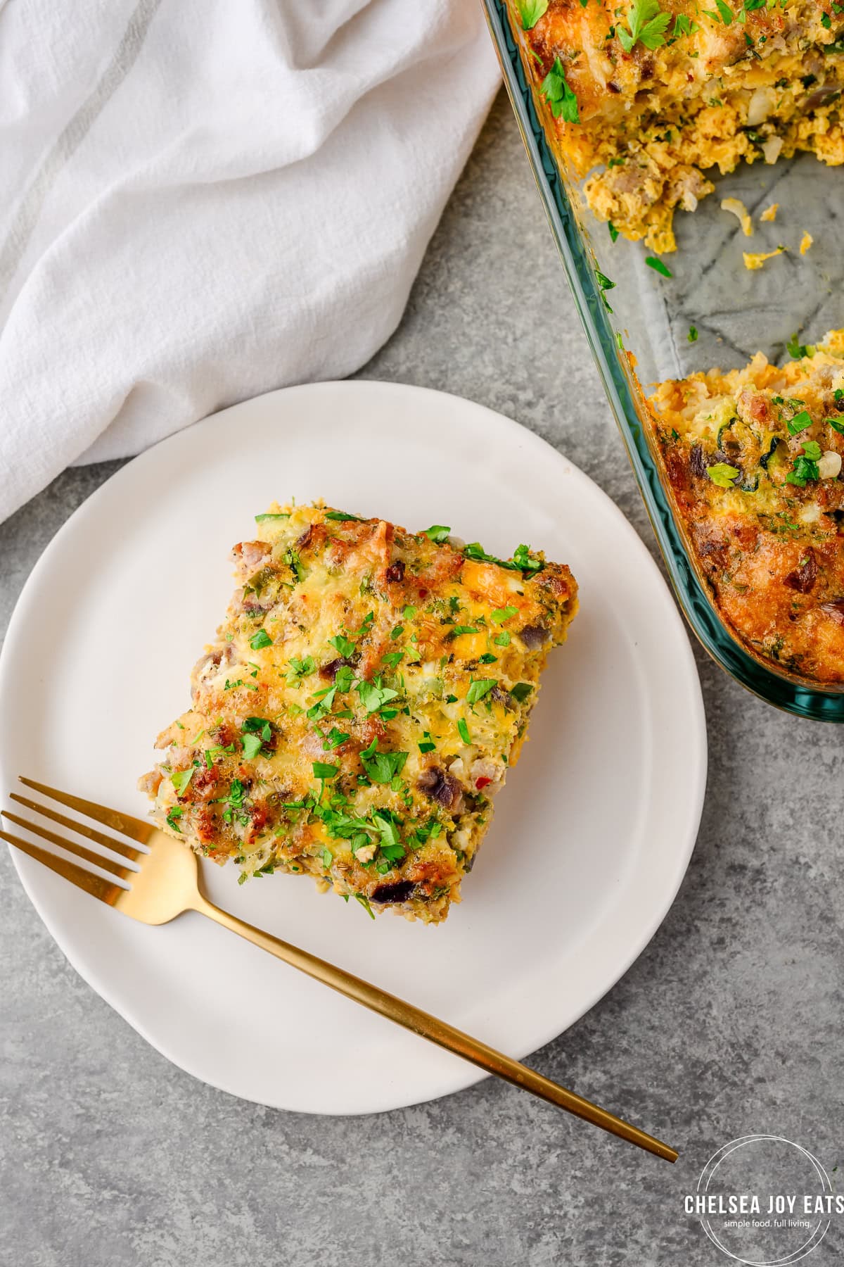 Serving of Zucchini Sausage Breakfast Casserole served on a white plate next to the casserole dish