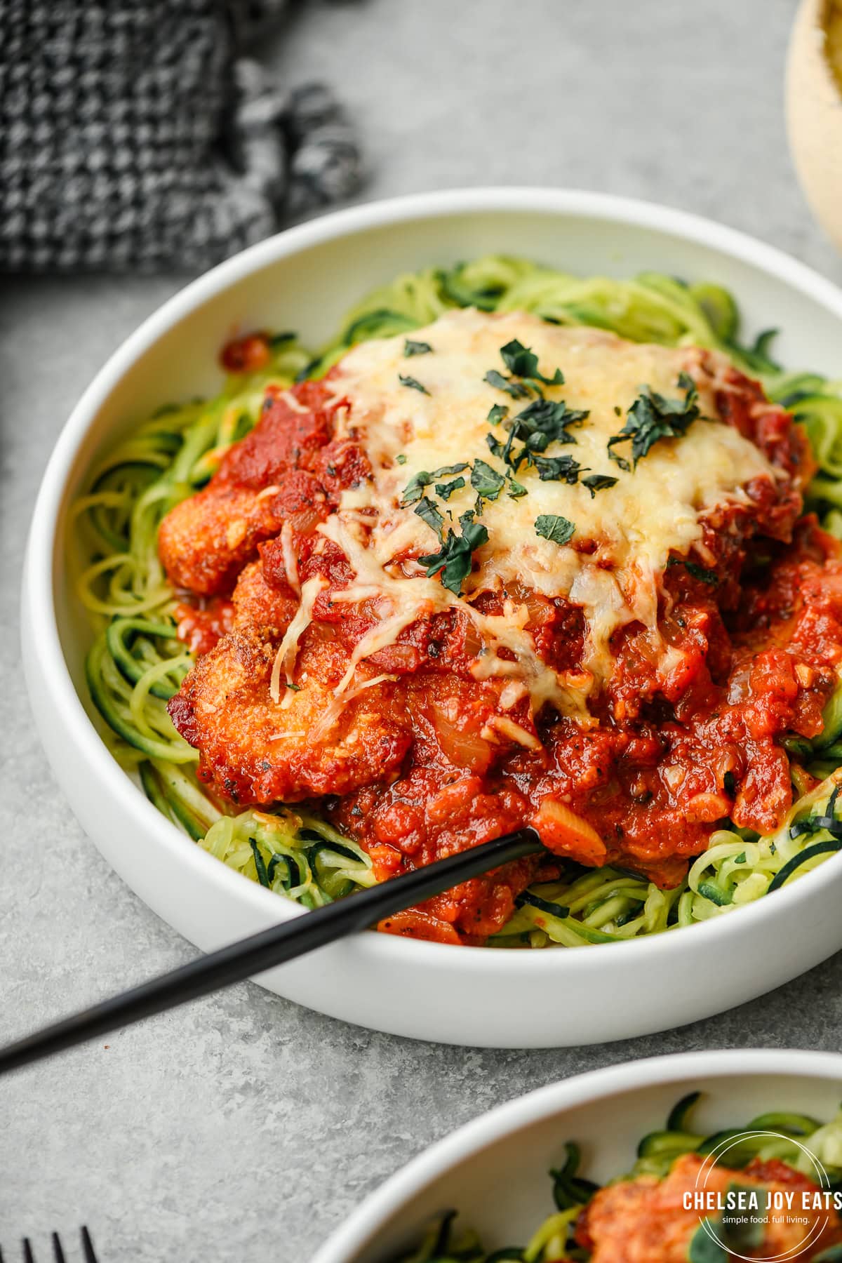 Closeup view of chicken parmesan served over zucchini noodles