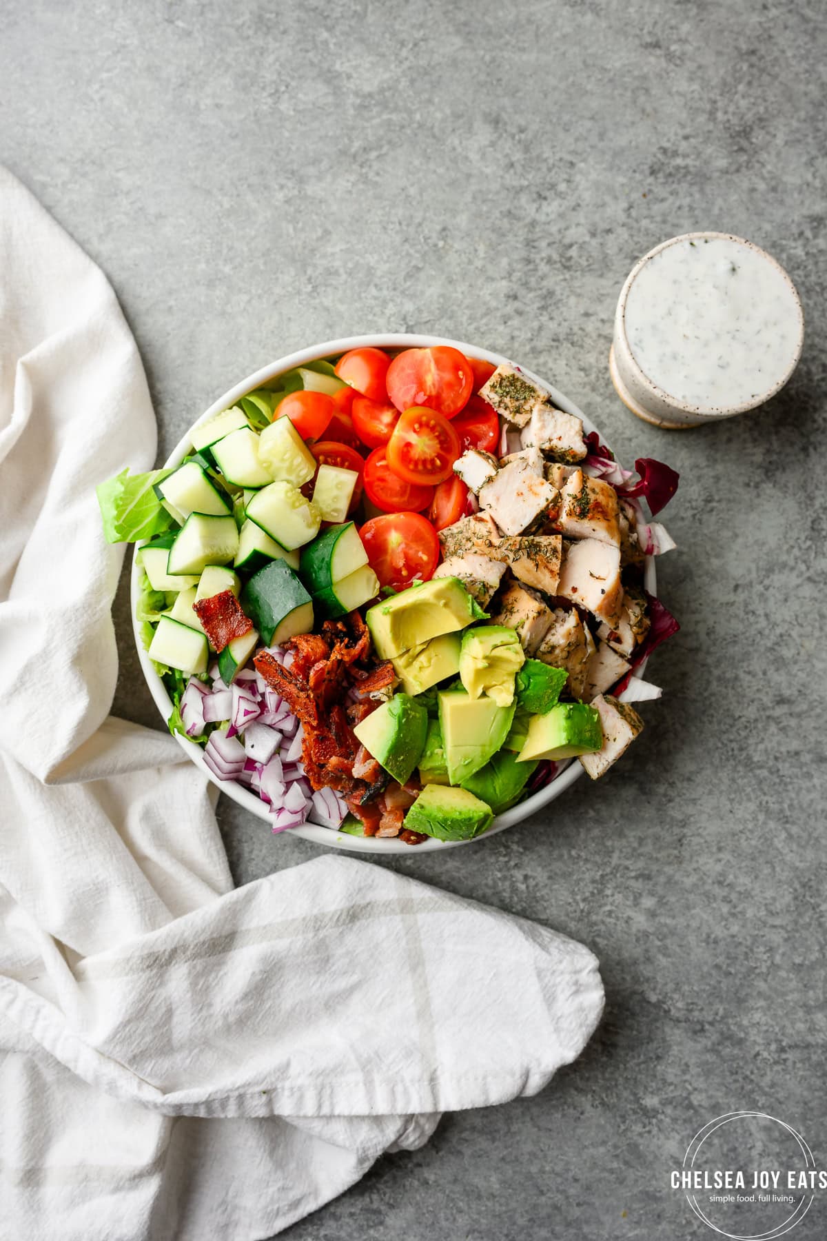 Overhead view of a chicken bacon ranch salad with Greek yogurt ranch on the side