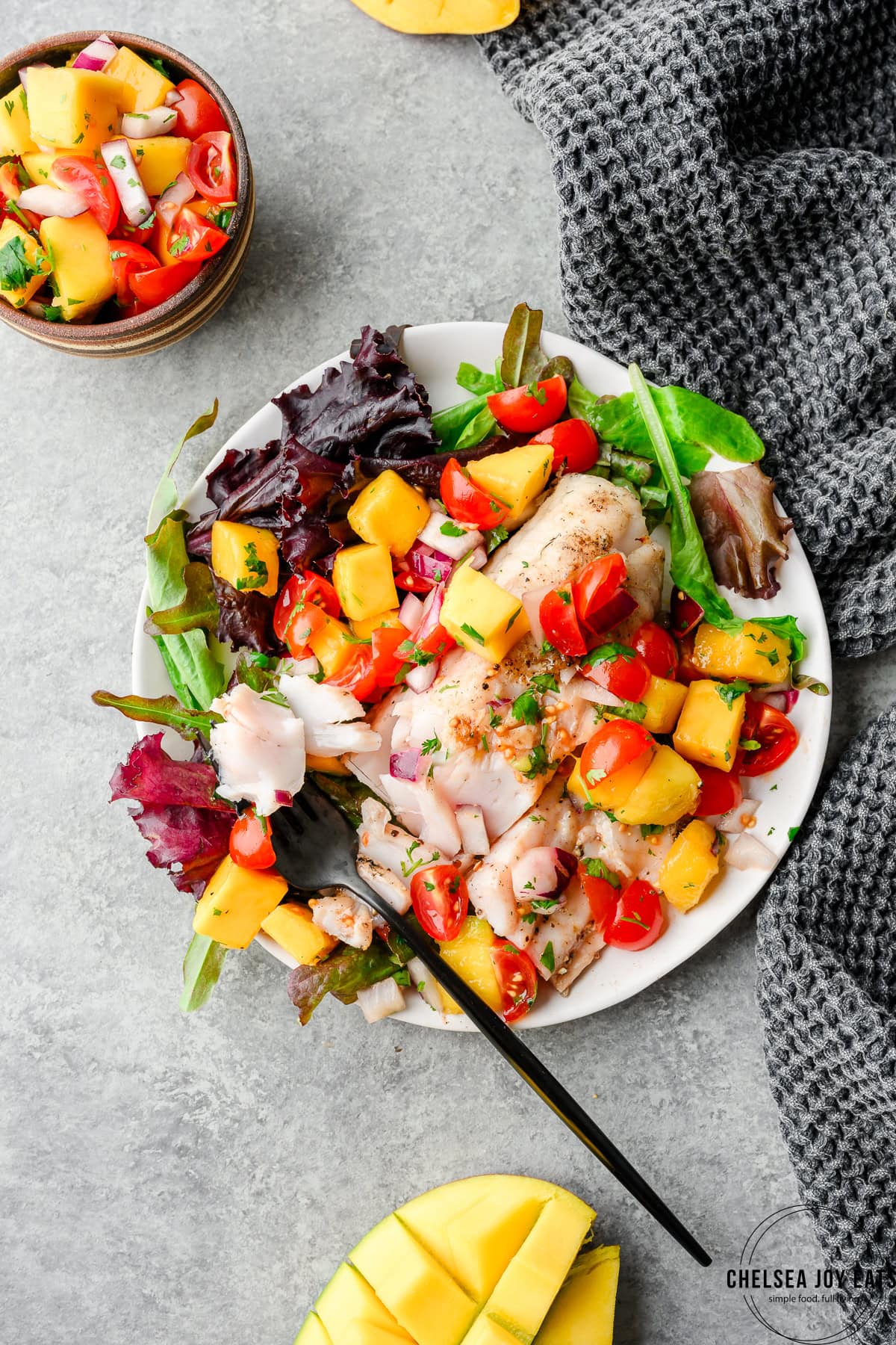Overhead view of grilled walleye meal with mango salsa and spring greens