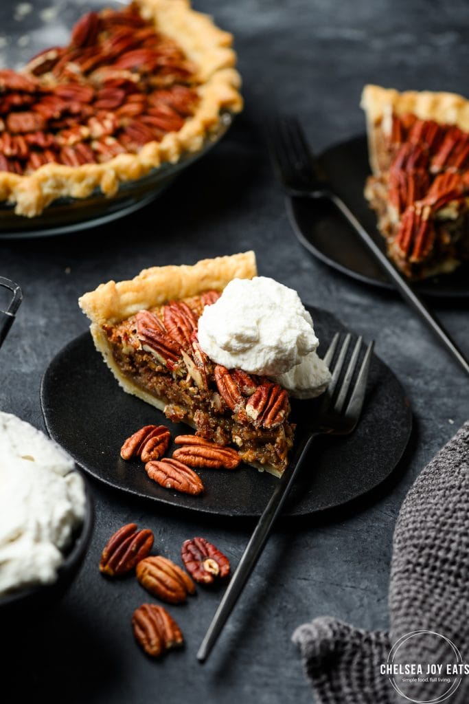 Slice of pecan pie topped with whipped cream