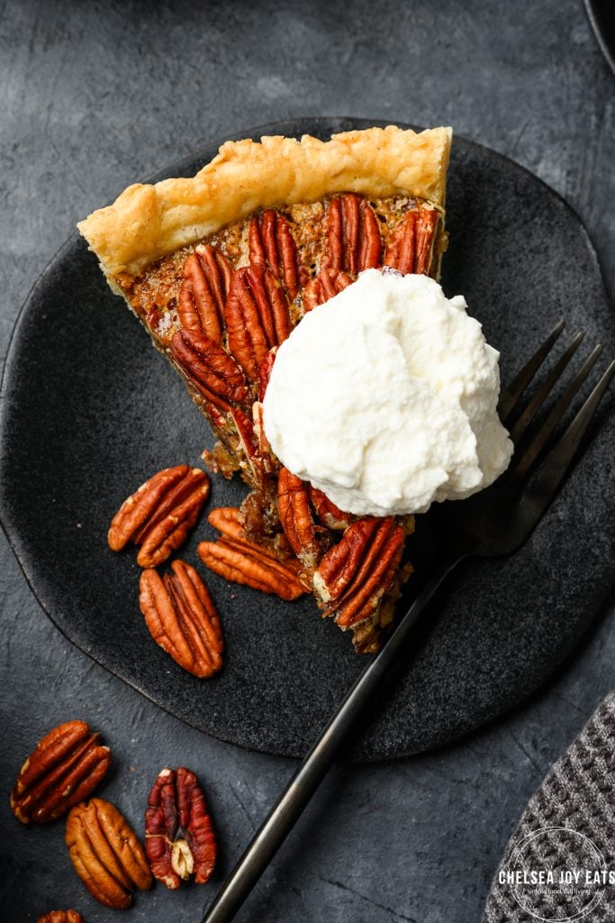 Slice of gluten free pecan pie, topped with whipped cream