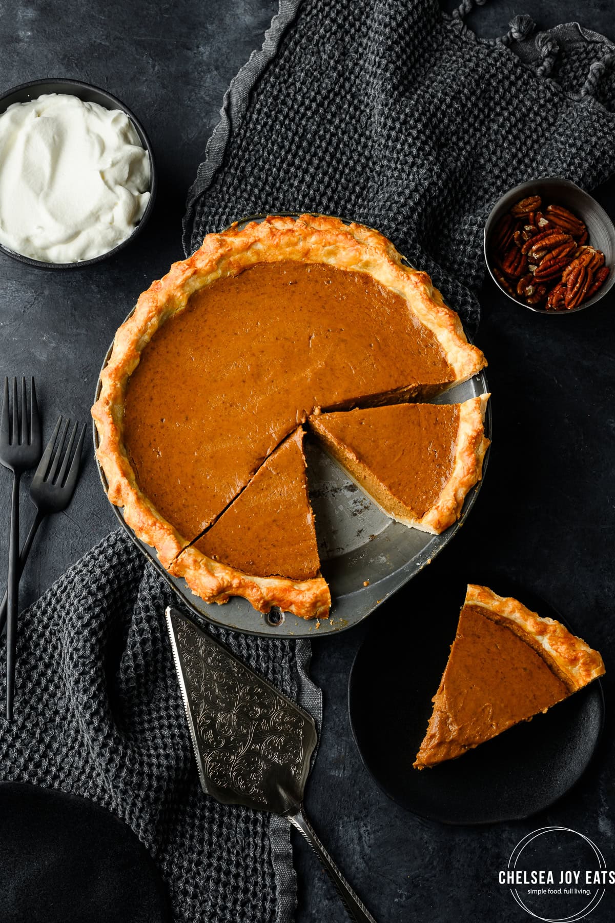 Pumpkin pie with a slice removed, with additional pieces sliced in the pan