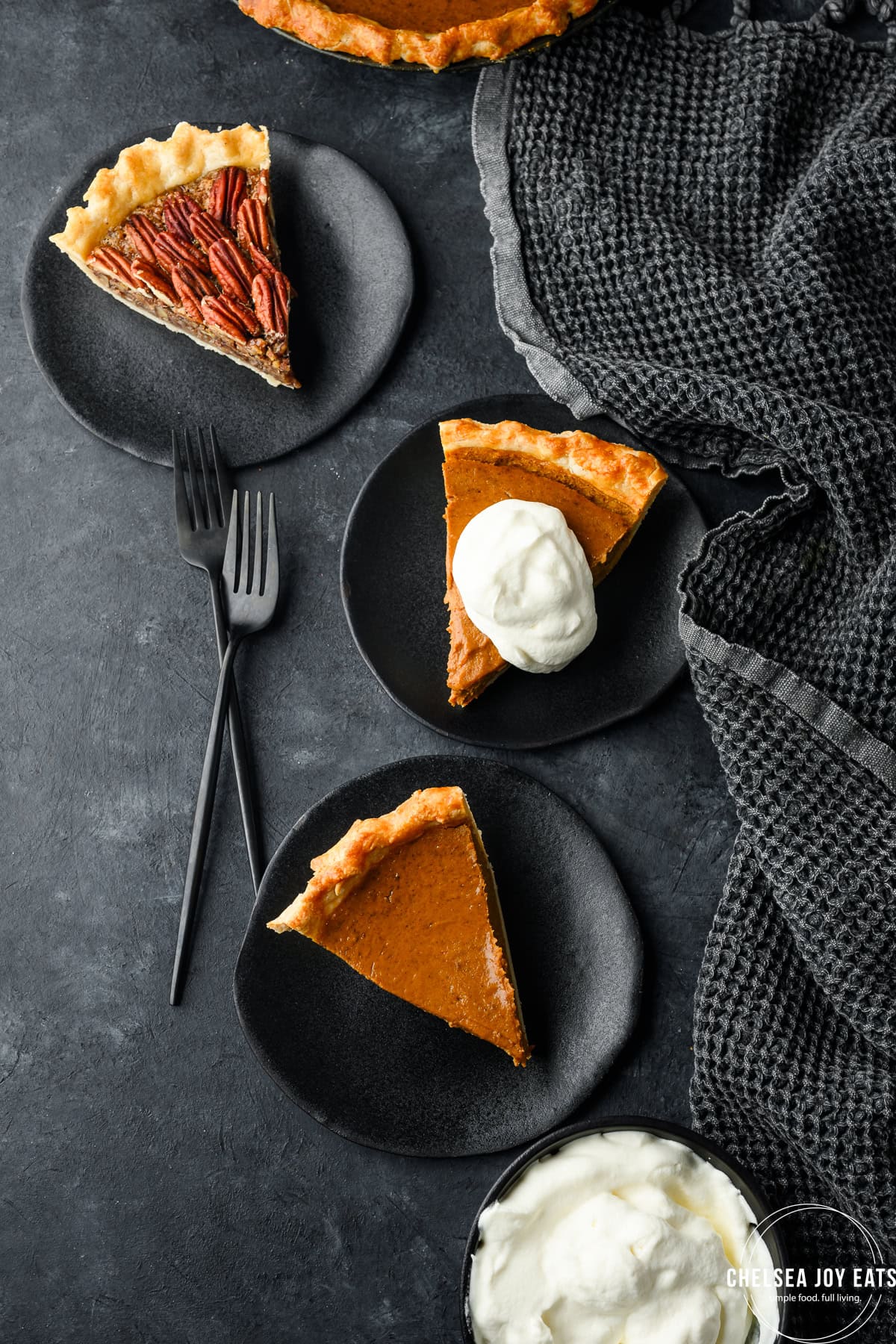 Plates with slices of gluten free pumpkin pie and gluten free pecan pie, plus a bowl of whipped cream