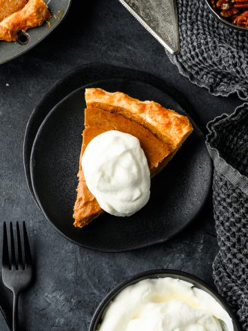 Piece of gluten free pumpkin pie on a plate with a dollop of whipped cream