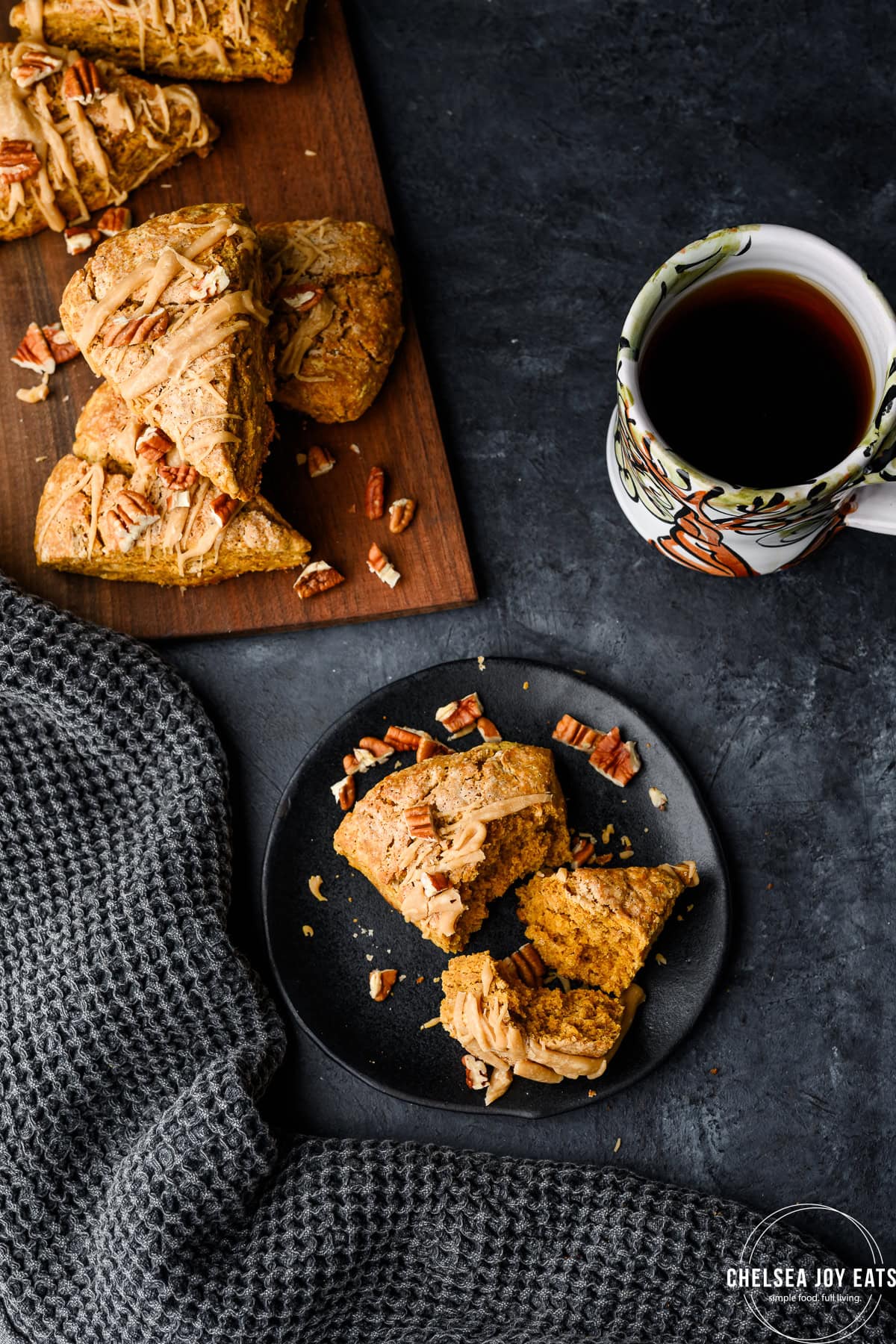 Overhead view of a partially-eaten gluten free scone next to a tray of scones and a mug of coffee
