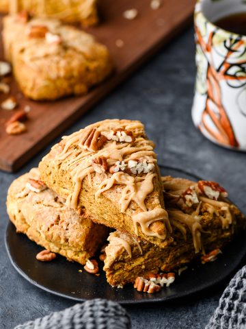 Gluten free pumpkin scones drizzled with maple icing piled on a plate