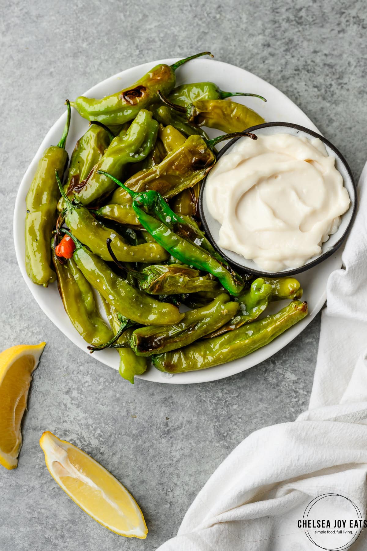 Plate of oven roasted shishito peppers with a dish of garlic aioli for dipping
