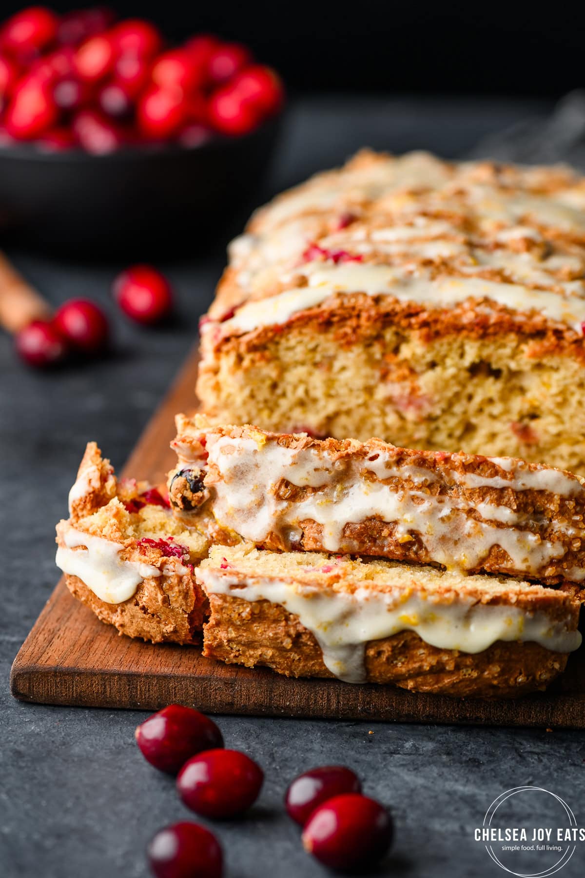 Closeup of slices of gluten free cranberry bread, with the remaining loaf in the background