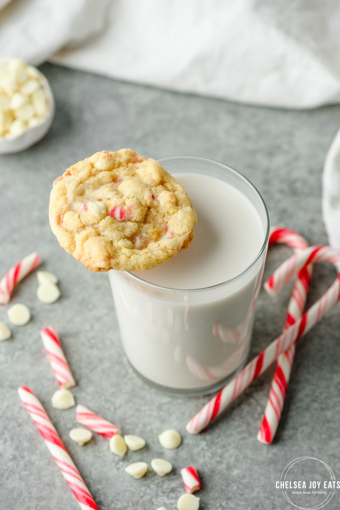 A gluten free white chocolate peppermint cookie balanced on a glass of milk