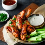 Tray with hot honey chicken wings, celery, and a blue cheese sauce