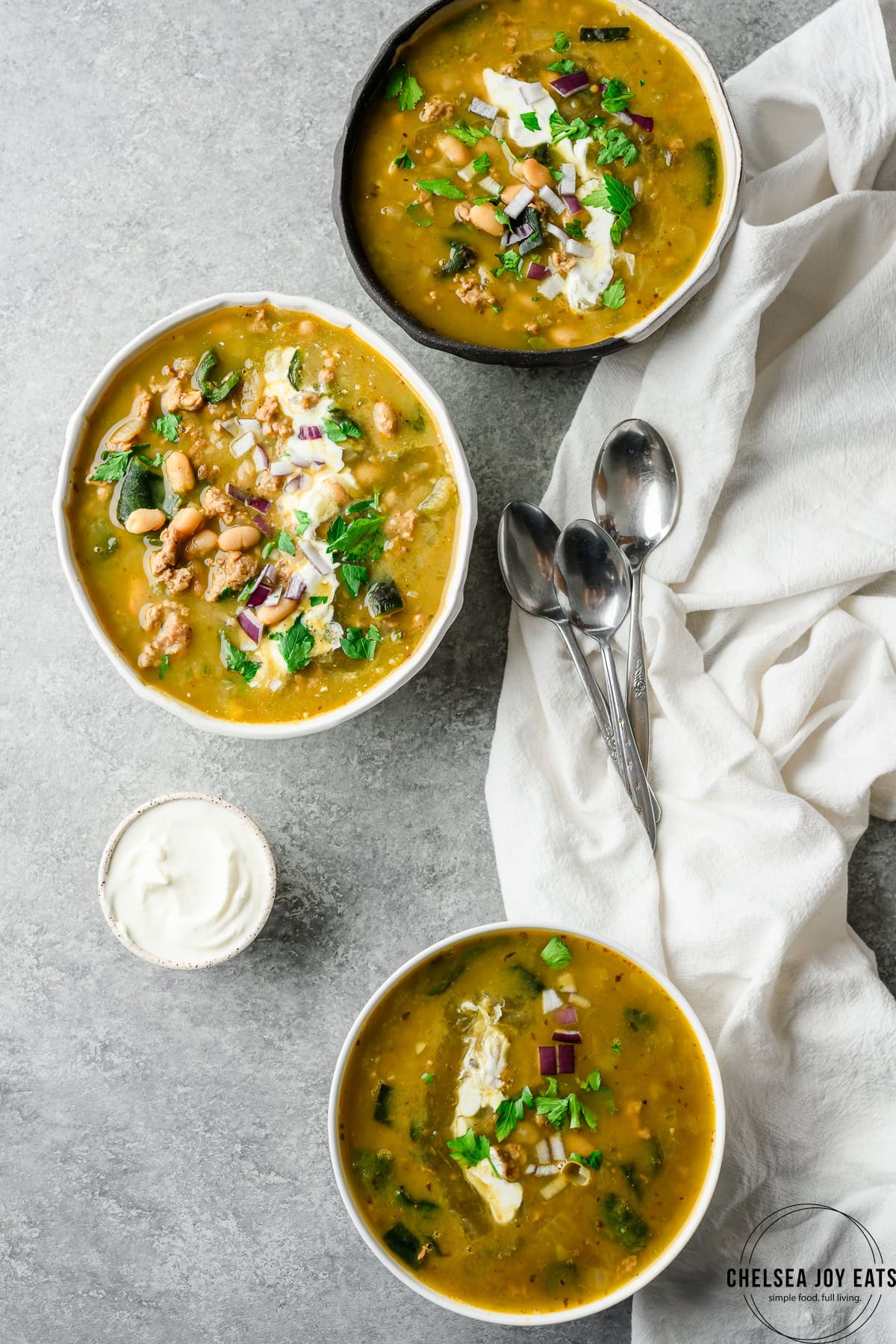 Bowls of white turkey and poblano chili with parsley and sour cream as garnish