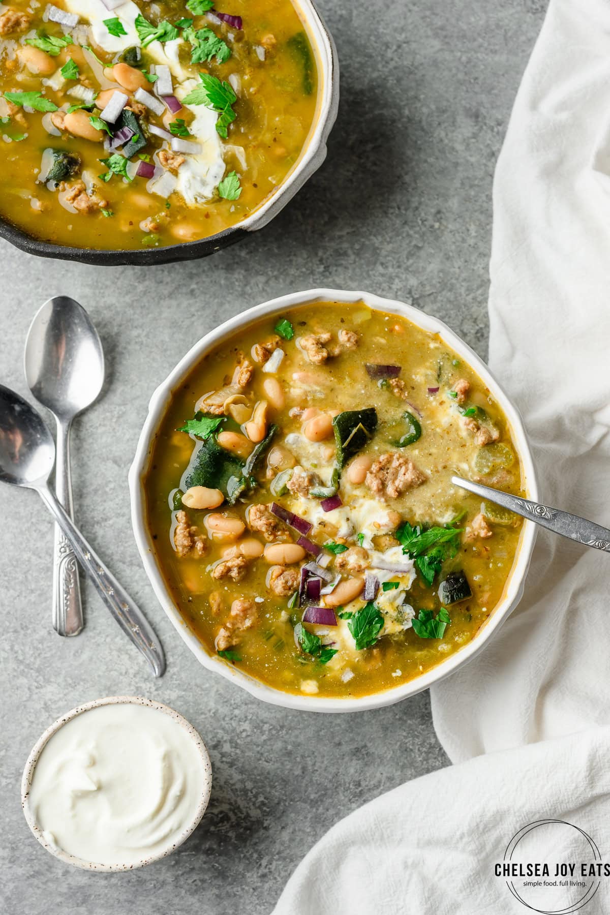 Bowl of ground turkey and poblano chili garnished with sour cream and parsley