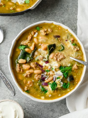 Bowl of white turkey and poblano chili garnished with sour cream and parsley