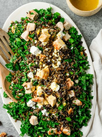 Platter with wild rice, kale, and chicken salad garnished with feta and raisins