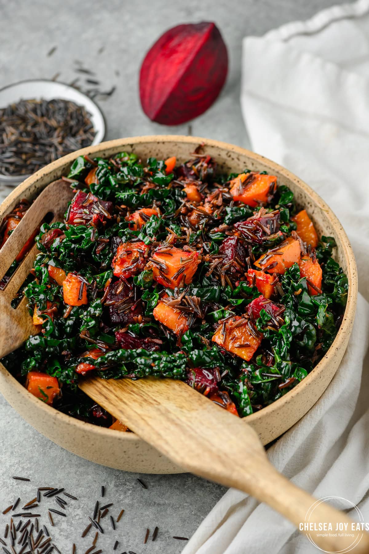 Roasted beet and butternut squash salad with wild rice tossed with dressing in a serving bowl