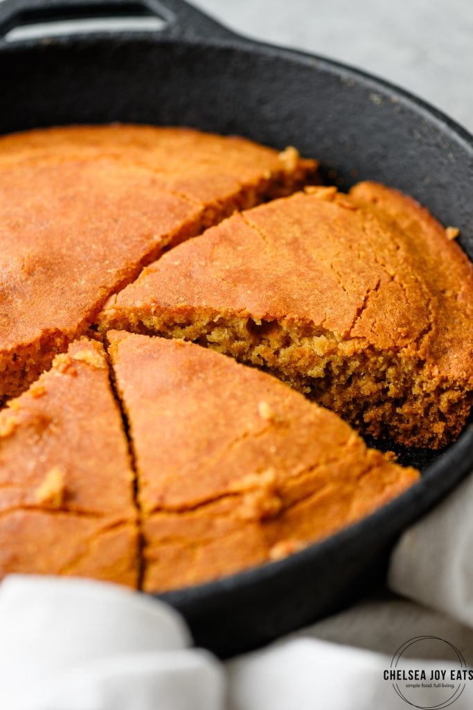 Closeup of a cut slice of cornbread in a cast iron skillet
