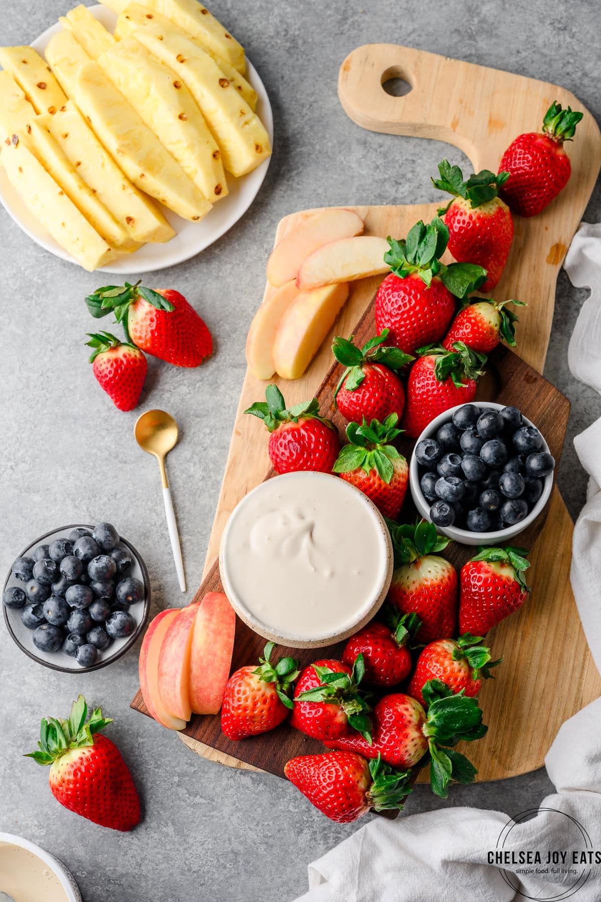 Bowl of gluten free fruit dip on a serving platter with strawberries, blueberries, and pineapple