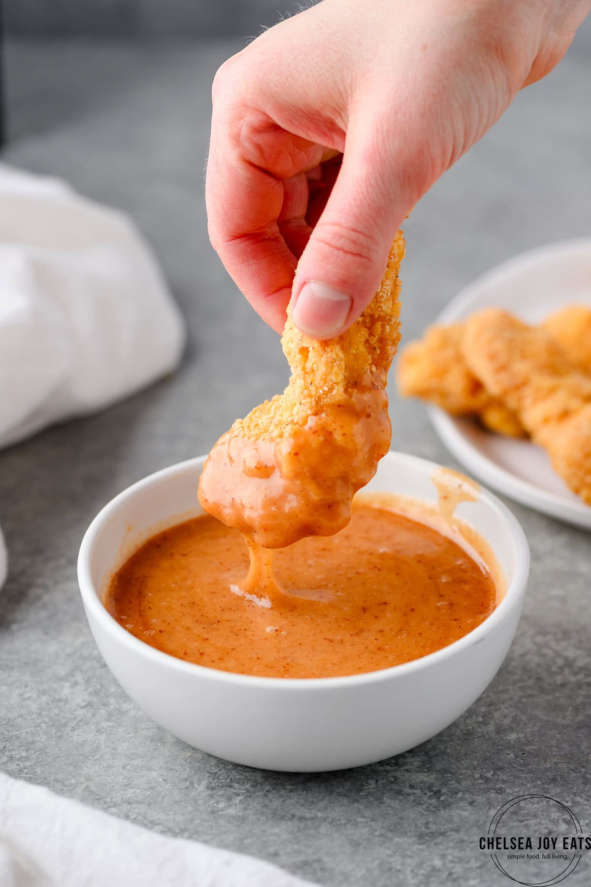 Dipping a chicken tender into hot honey mustard sauce
