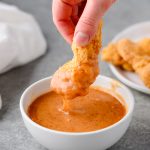 Chicken tender dipped into hot honey mustard sauce