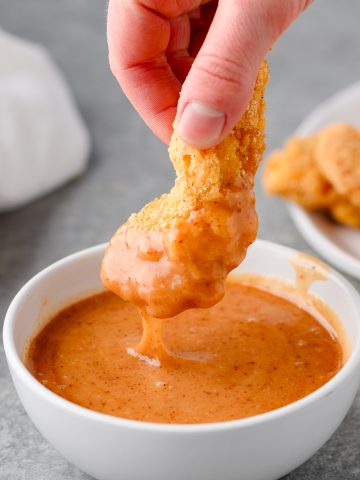 Chicken tender dipped into hot honey mustard sauce
