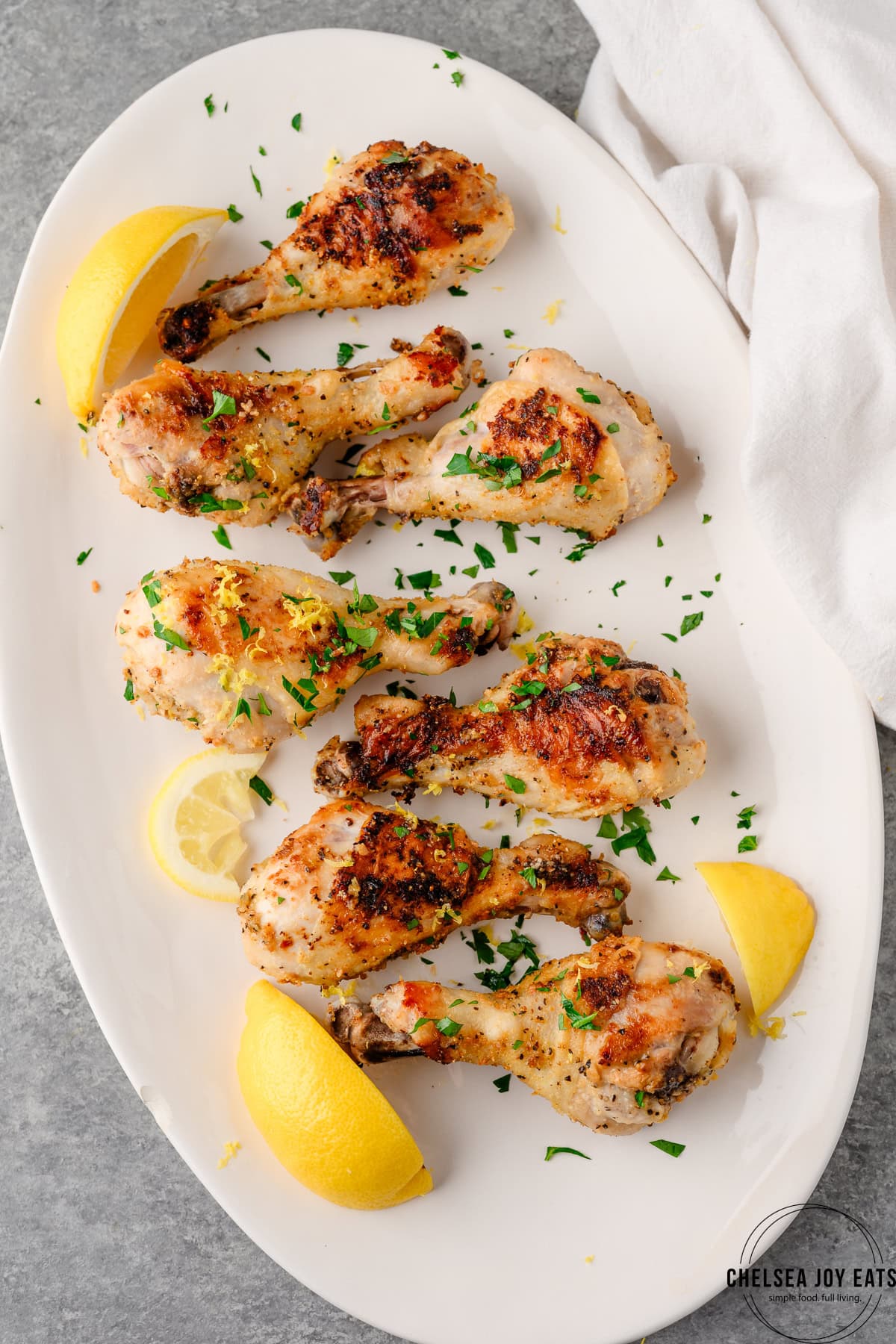 Platter with lemon pepper chicken drumsticks garnished with lemon slices and parsley